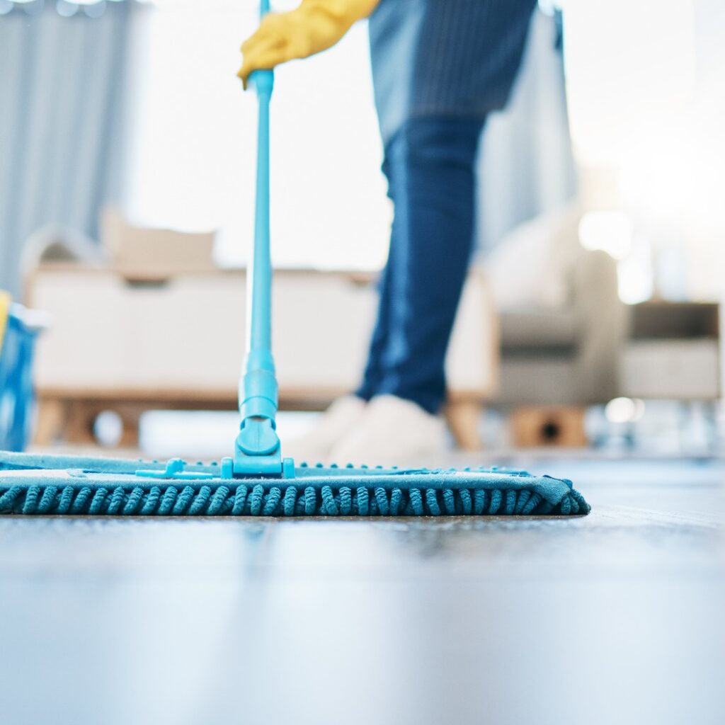 Hauswirtschaft, Reinigung und Hausmädchen mit einem Mopp, um den Boden im Wohnzimmer eines Hauses zu reinigen. Weibliche Hausangestellte, Putzfrau und Hausfrau, die den Boden in ihrem Haus von Bakterien, Staub und Schmutz befreit.